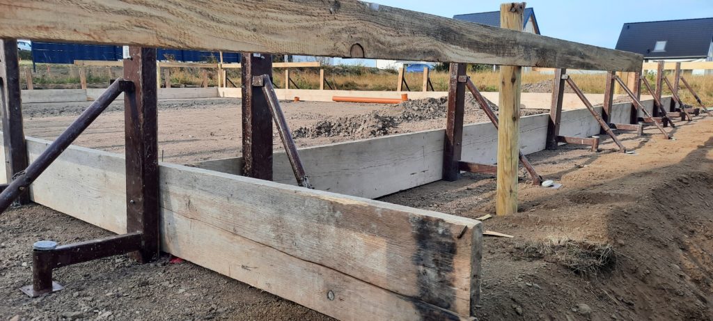 Der verdichtete Schotter mit Begrenzer für den Beton der Bodenpatte